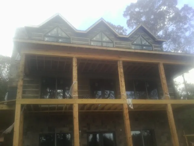 Dormers and porch framing on a large log home under construction — Roof Coating work by our crew in Lake George